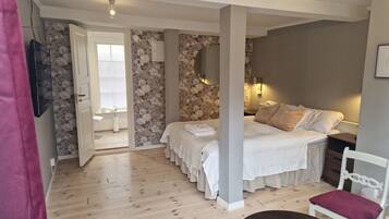 A bedroom with a bed, a chair, a bedside table, a lamp, and a window.