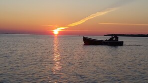 A sunset over a calm sea with a boat in the foreground. - Hotell Klockargården (Öregrund)