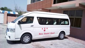 Een witte bestelwagen met de tekst 'Bete Daniel Hotel' en een websiteadres geparkeerd voor een gebouw.