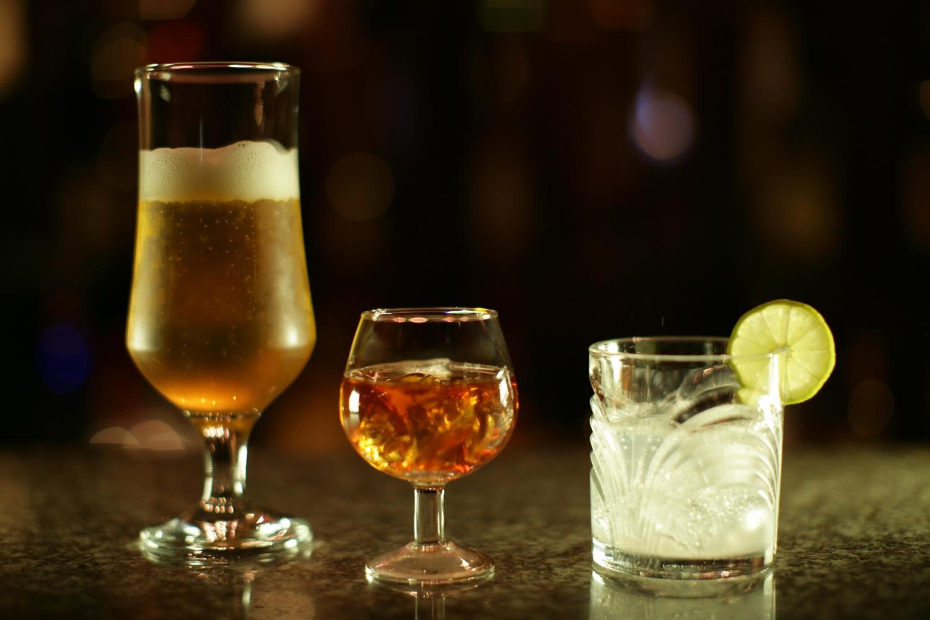 Tres vasos de bebidas diferentes sobre una barra.