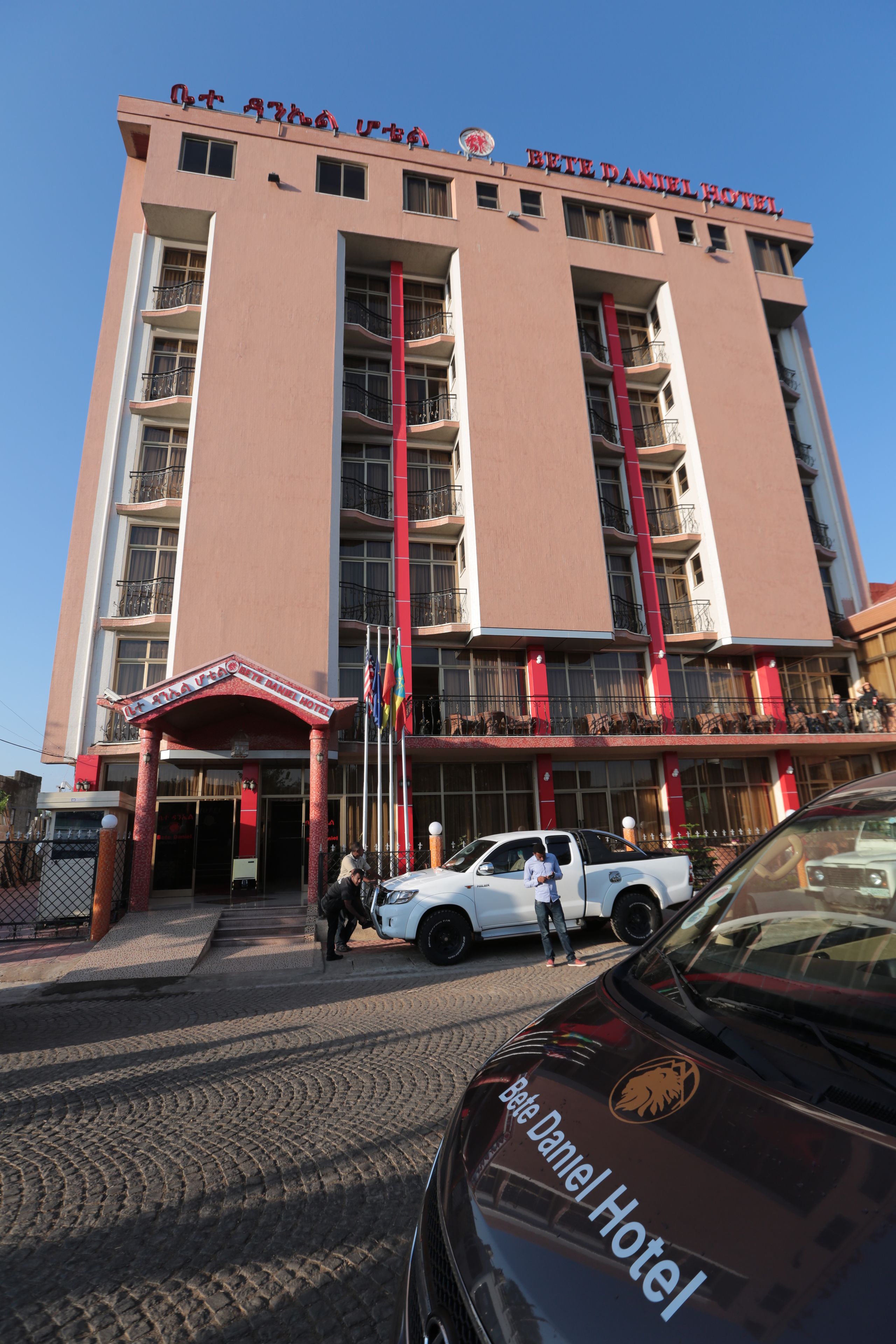 A multi-story hotel with balconies and a central entrance.