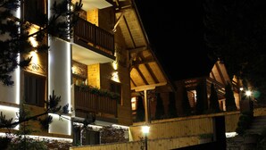 Un edificio de madera de varios pisos con balcones, fachada de piedra y una entrada bien iluminada.