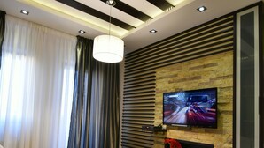 Una sala moderna con un sofá modular, una mesa de centro de madera, un televisor de pantalla plana montado en una pared de piedra y una chimenea.