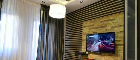 Una sala moderna con un sofá modular, una mesa de centro de madera, un televisor de pantalla plana montado en una pared de piedra y una chimenea.