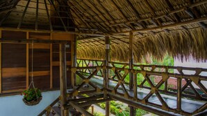 A wooden structure with a thatched roof, wooden railings, and a hanging plant.
