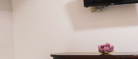 Habitación de hotel con cama, televisor de pantalla plana montado en la pared y cabecero de madera.