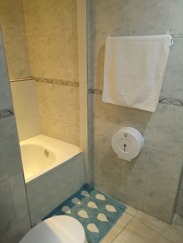 A bathroom with a bathtub, toilet, and a towel rack. - Motel Lavapiés (Madrid)