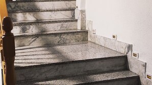 Una escalera de mármol con barandilla que lleva a un piso superior.