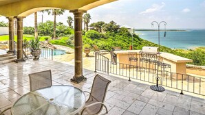 Eine Terrasse mit Glastisch und Stühlen, mit Blick auf einen Pool und den Ozean.