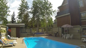 Una piscina al aire libre con sillones de descanso y zona de barbacoa.