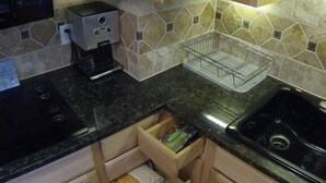 Una cocina con armarios de madera, encimera negra, lavavajillas integrado y salpicadero de azulejos.