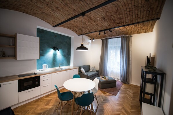 A modern kitchen with a white countertop, built-in oven, and a dining area with a round table and chairs.