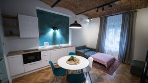 Ett modernt kök med en stor köksö, en matplats med ett runt bord och stolar samt ett mysigt sovrum med en säng och gardiner.
