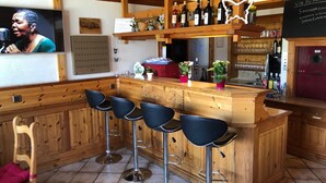 A bar area with wooden bar stools, a shelf with bottles, and a chalkboard menu.