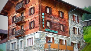 A hotel with a stone facade and wooden upper levels, featuring balconies and a sign indicating it is a restaurant.