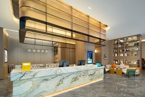 Un espace d’accueil moderne doté d’un comptoir en marbre, de sièges et d’un intérieur bien éclairé.