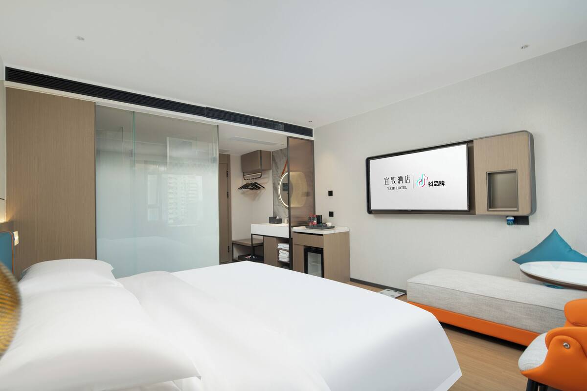 Ein modernes Hotelzimmer mit einem großen Bett, einem Schreibtisch, einem Sessel und einer kleinen Couch.