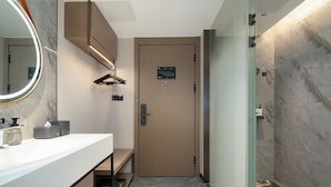 A modern bathroom with a wooden door, a mirror with a light, a sink with toiletries, and a shower area. - Yizhi Hotel Rainbow Bridge Subway Gz (Guangzhou)