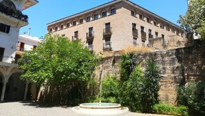 Een historisch gebouw met een binnentuin, inclusief een fontein en weelderig groen.