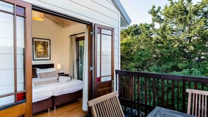 A bedroom with a bed, a bedside table, and a window. - House at Longbeach - upstairs apartment (Noordhoek, Chapmans Peak, Cape Town)