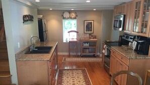 A kitchen with wooden cabinets, granite countertops, a stainless steel sink, and a built-in oven. - Guest House 632 Summit Street (Alton)
