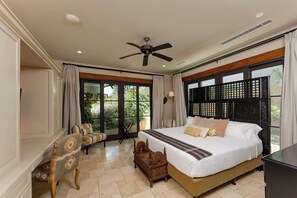 Une chambre spacieuse avec un grand lit, un ventilateur de plafond et une vue par la fenêtre.