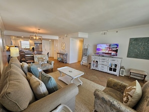 A living room with a sofa, armchairs, a coffee table, a TV, and a kitchen in the background. - Beautiful beachfront condo with Stunning Gulf Views!! 4061 BS1 (Miramar Beach)
