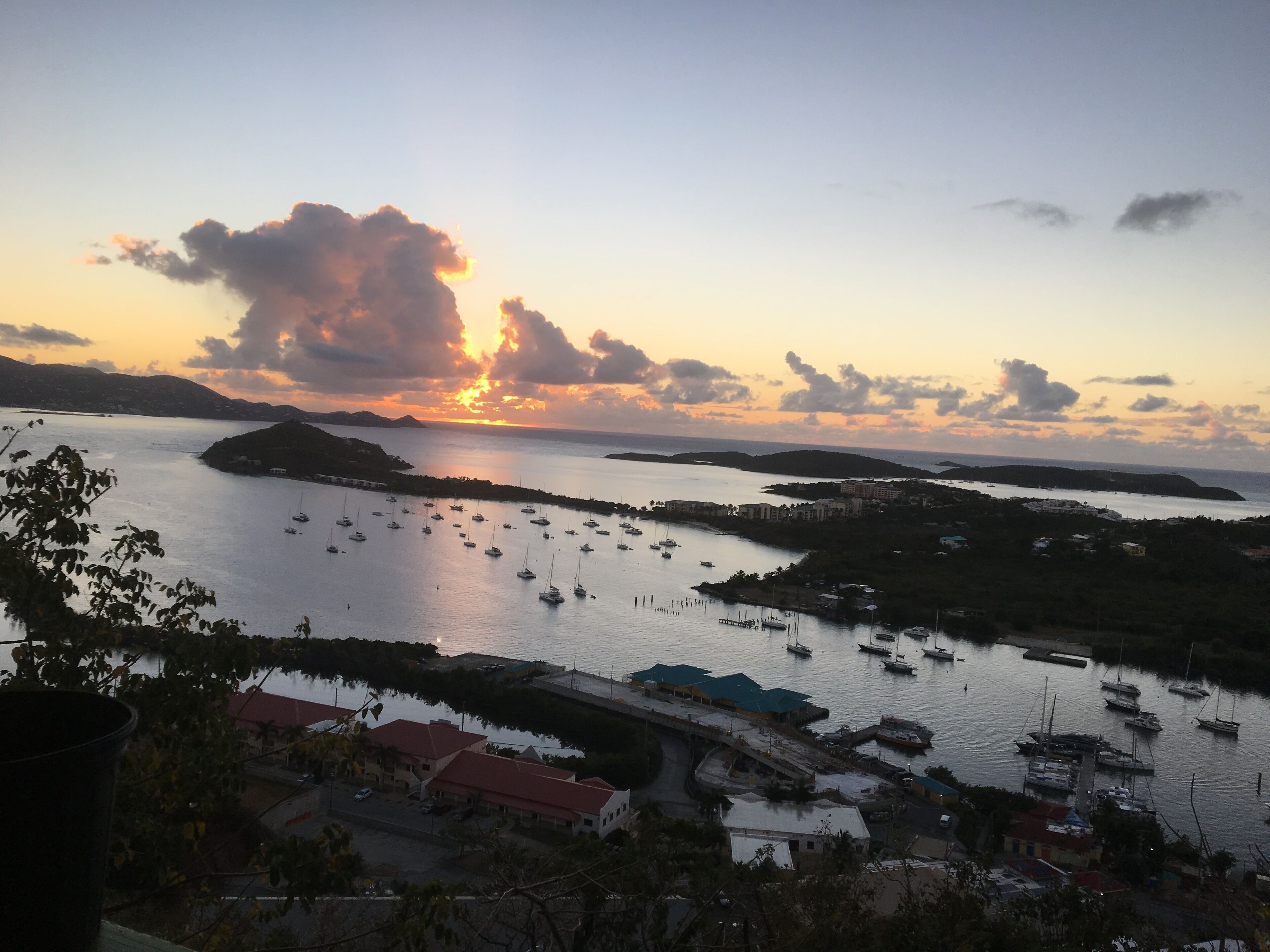 Un pueblo costero con un puerto deportivo, barcos y edificios de techos rojos.