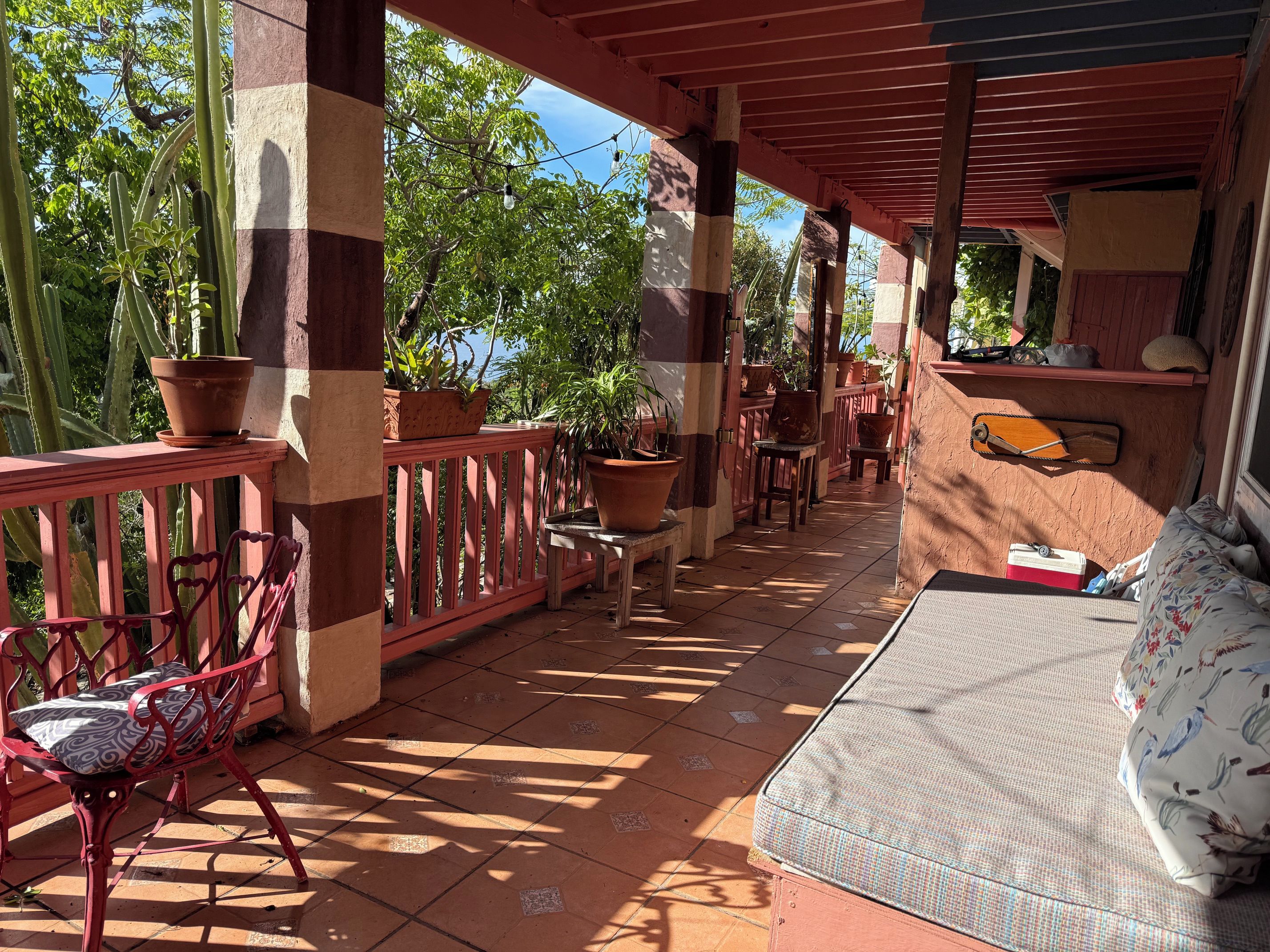 A covered outdoor area with a seating arrangement, potted plants, and a wooden bench.