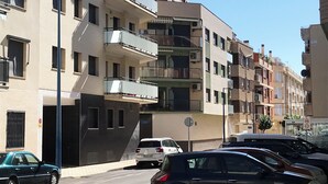 Ein mehrstöckiges Wohngebäude mit Balkonen, einem Parkplatz und blauem Himmel.