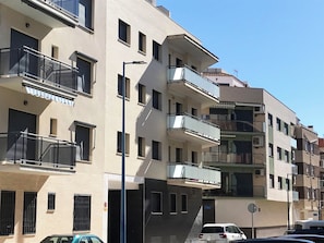 Un immeuble résidentiel à plusieurs étages, doté de balcons, d’un escalier et d’un espace de stationnement.