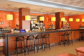 A bar area with a long counter, multiple bar stools, and a variety of bottles and snacks. - Lido (Benidorm)