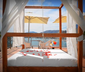 A balcony with a bed, white curtains, and a view of the sea and mountains. - Lido (Benidorm)