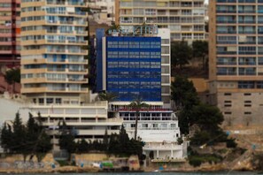 Un hotel a più piani con una facciata blu ben visibile, circondato da altri edifici.