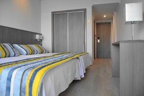 Una camera d'albergo moderna con un letto grande, un comodino, una lampada e un armadio.