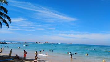Una playa con gente nadando y caminando por la orilla.