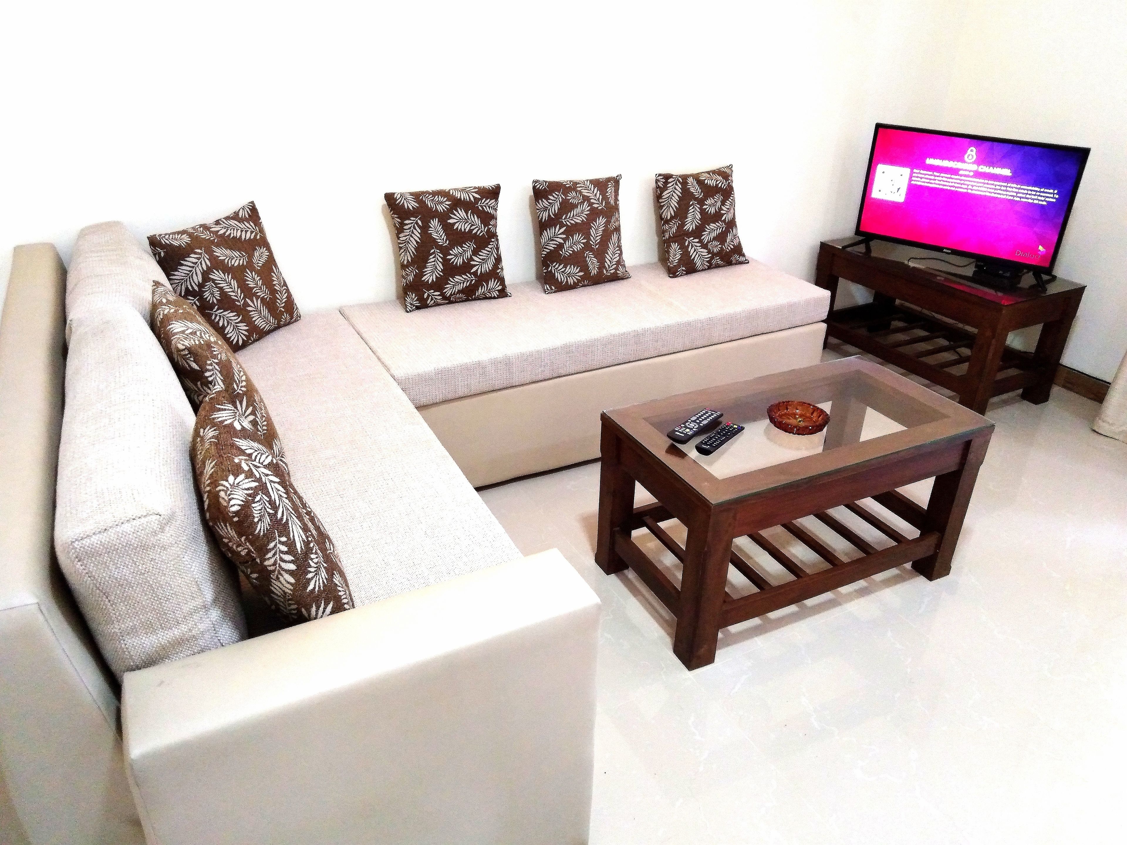 A living room with a sofa, a glass coffee table, and a television.