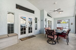 A spacious patio area with a dining table, chairs, and a ceiling fan.