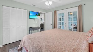 Une chambre à coucher comprenant un lit, un bureau, un téléviseur et un ventilateur de plafond.