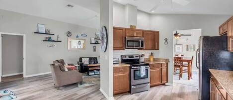 A modern kitchen with wooden cabinets, a stainless steel oven, and a microwave.