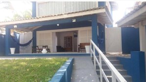 Un edificio de dos pisos con un porche cubierto, una escalera y un pequeño jardín.