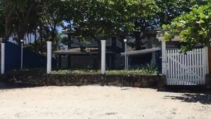 Un espacio al aire libre con arena, un muro de piedra, una cerca blanca y un edificio al fondo.