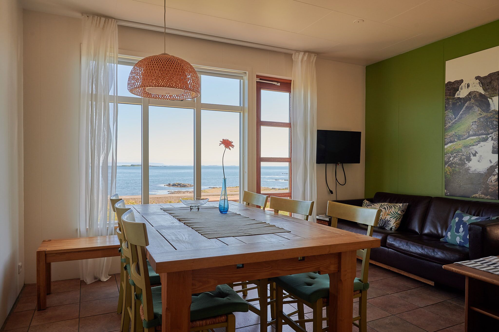 Een eetgedeelte met een tafel, stoelen, een bank en een televisie.
