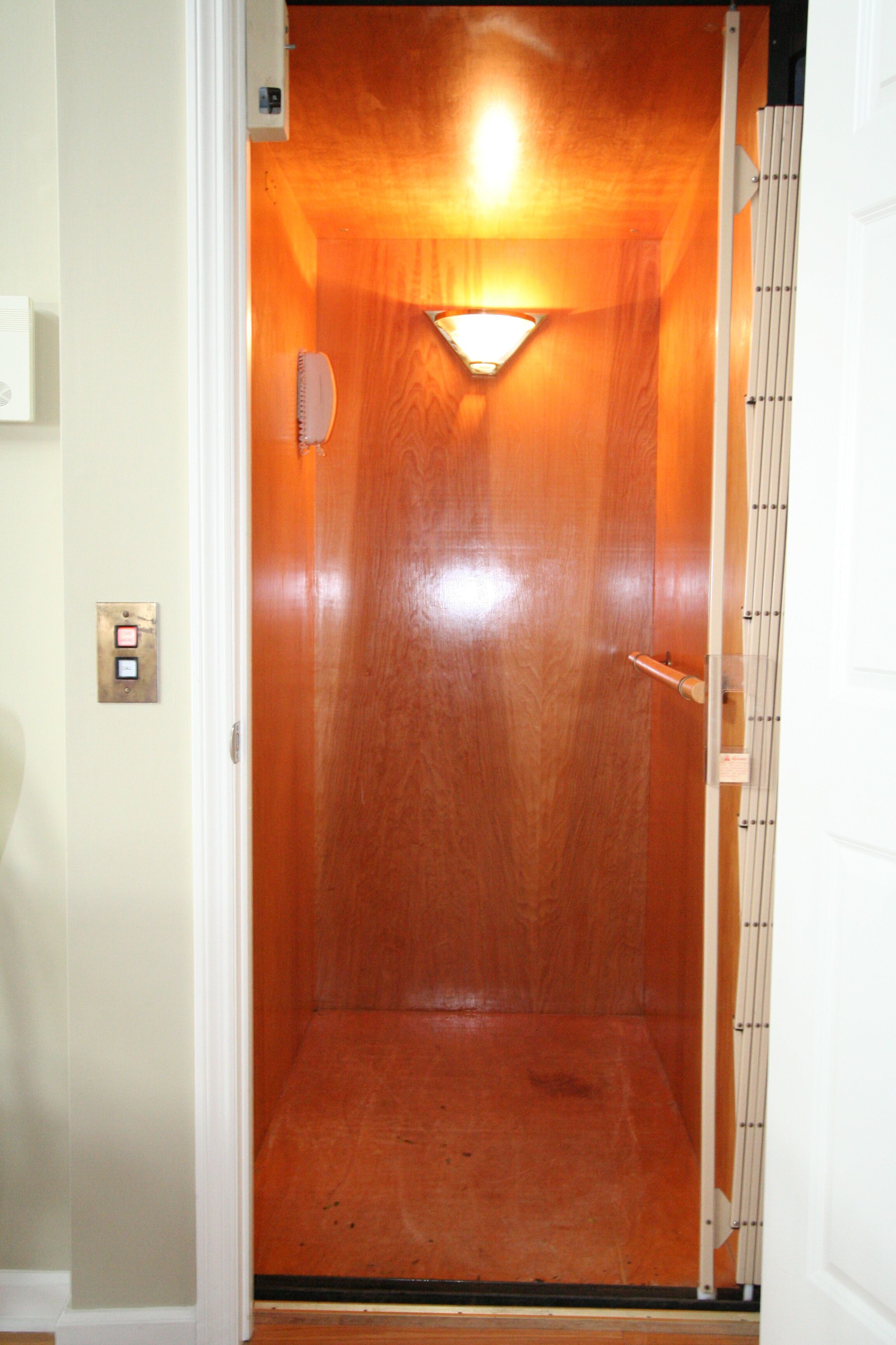 Un ascensor con interior de madera y una lámpara en la parte superior.