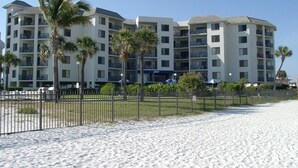 A beachfront hotel with multiple floors, balconies, and palm trees.