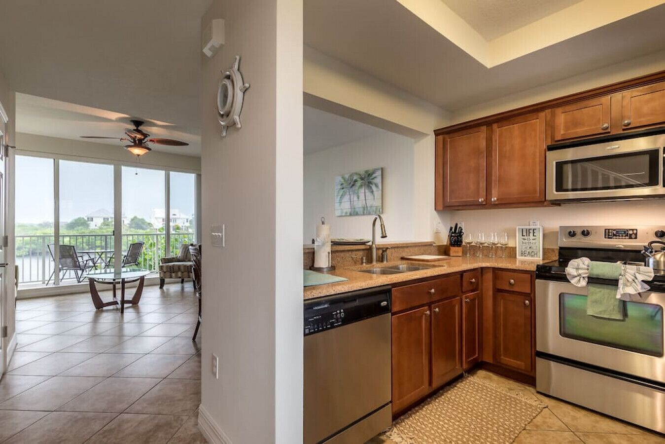 A modern kitchen with wooden cabinets, stainless steel appliances, and a large window overlooking a balcony.