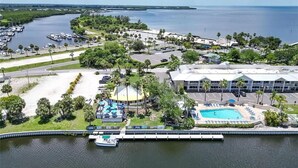 Ein Luftbild eines Küstenhotels mit Schwimmbad, einem Hafen mit Booten und einem großzügigen Gebäude mit flachem Dach.