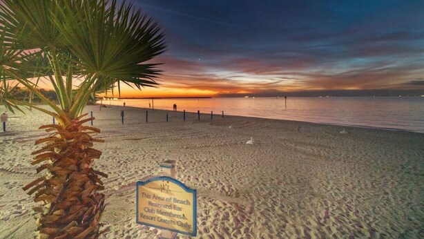 Ein Strand mit einer Palme und einem Schild, das anzeigt, dass er nur für Clubmitglieder und Hotelgäste reserviert ist.