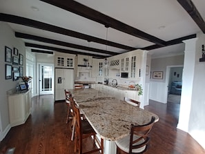 A spacious kitchen with a large island, wooden chairs, white cabinetry, and a dark ceiling. - Peace on the Brewers River with Panoramic Views. (Carrollton)