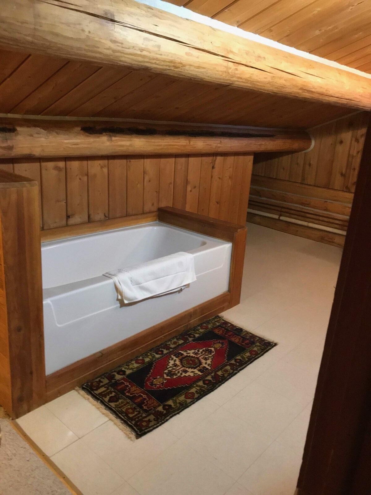 Eine Holzhütte mit freistehender Badewanne unter einer geneigten Decke.